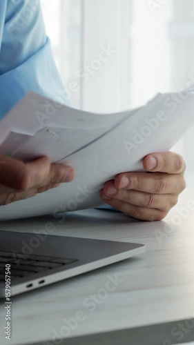 A businessman in a bright and modern office reads paper documents.
Office worker with documents.
Filling out documents and forms.
Organization of the work process.
Planning and organization