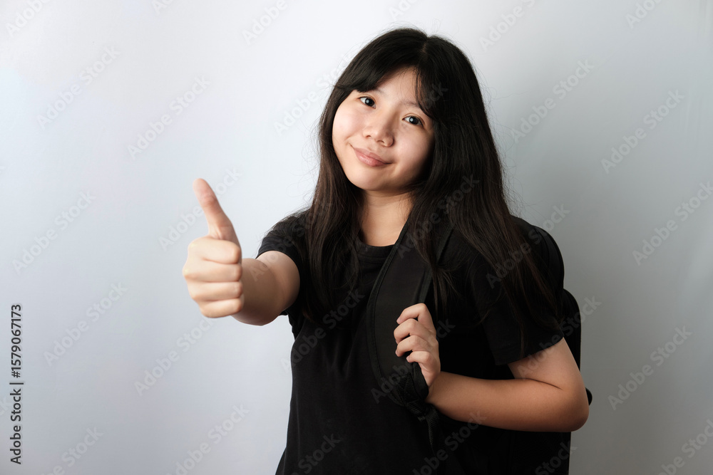 Asian girl in black t-shirt carrying backpack Giving Thumbs Up Asian girl in black t-shirt carrying backpack Giving Thumbs Up