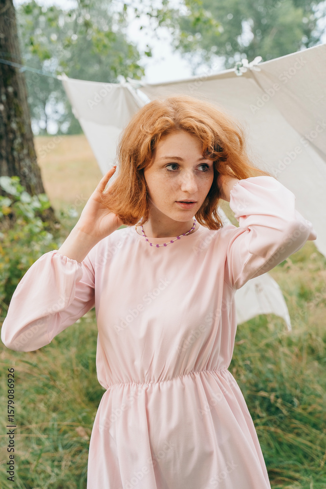 Naklejka premium Red-haired Woman in Pink Dress Outdoors with Linen Background