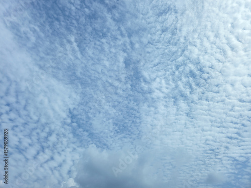 Blue Sky with White Fluffy Clouds. Natural Background for Weather, Nature, and Travel Concepts. High resolution sky texture wallpaper.