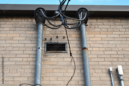 Принти на полотні Two weatherheads on brick building. AC electrical hookup.