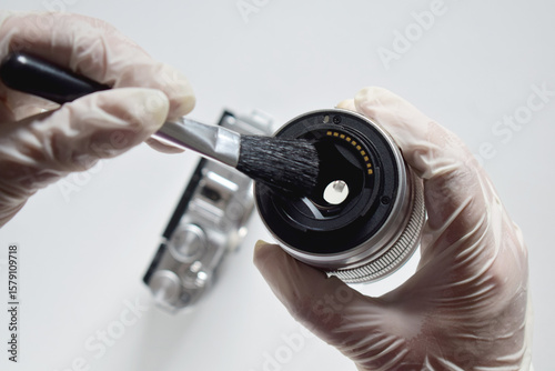 A camera repairman is cleaning the sensor and lens with a brush.