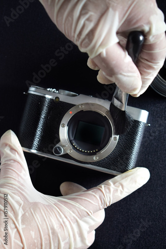 A camera repairman is cleaning the sensor and lens with a brush.