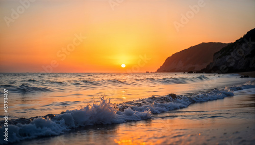 A serene photograph of a calm ocean at sunset, featuring gentle waves in the foreground reflecting warm golden and orange hues from the setting sun. The horizon includes silhouetted cliffs on the righ