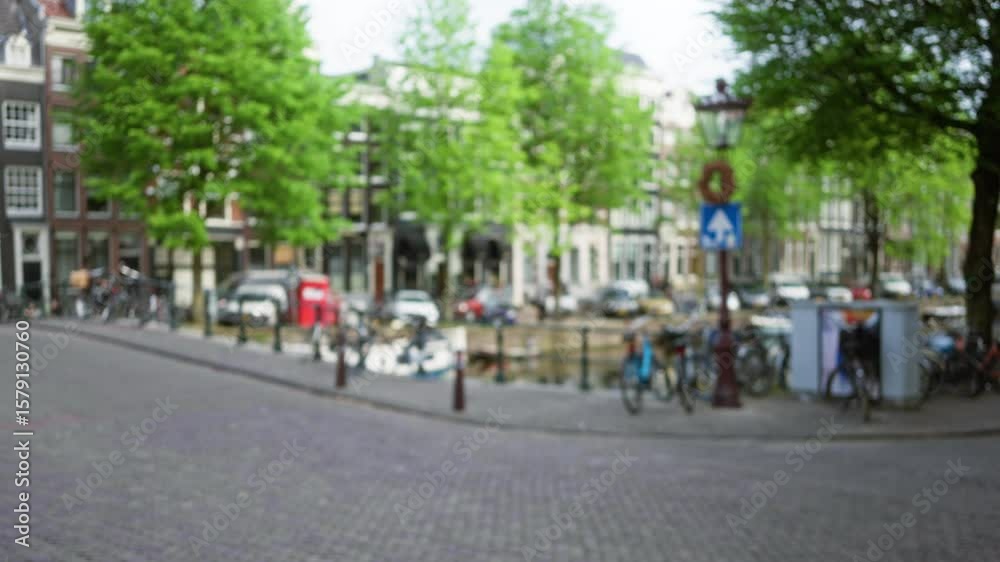 Blurry amsterdam city street with defocused urban scene featuring bicycles, cobblestone, trees, and canal in the netherlands, captured in artistic bokeh style. Blurry amsterdam city street with defocused urban scene featuring bicycles, cobblestone, trees, and canal in the netherlands, captured in artistic bokeh style.