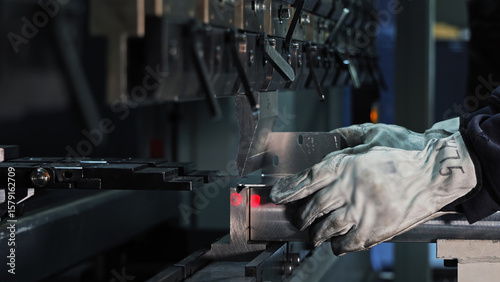 Worker operating CNC press brake machine. Close-up of a worker using a CNC press brake to bend sheet metal in a precision manufacturing or industrial setting.