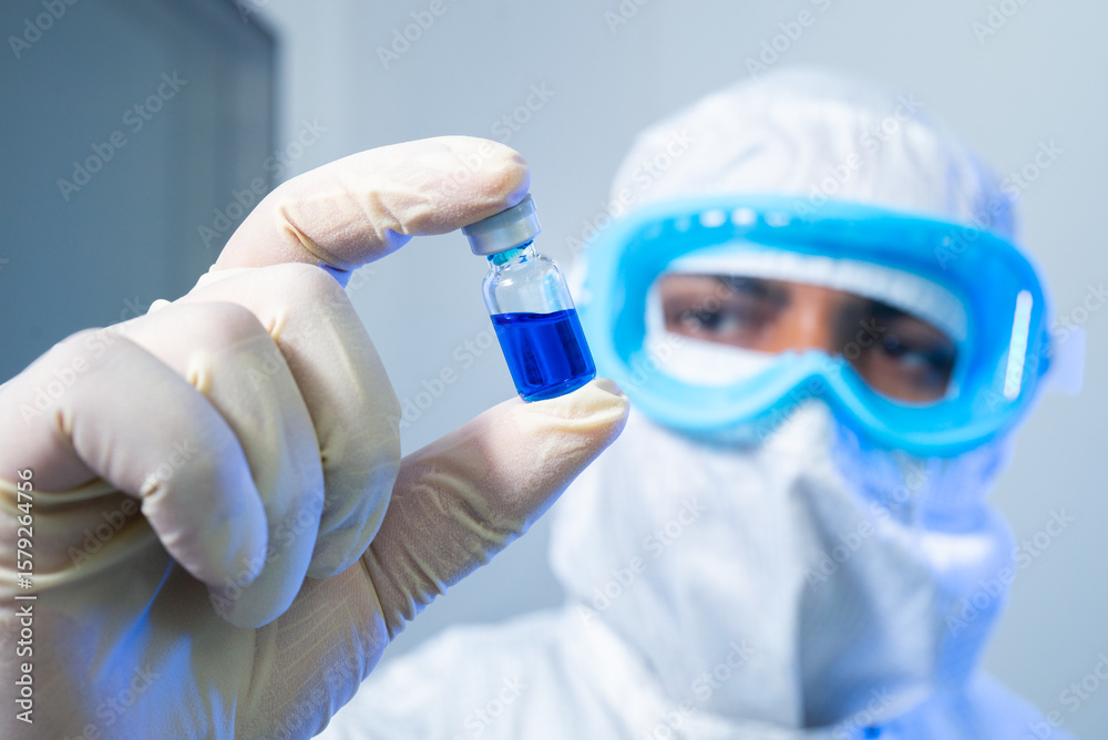 liquid injection close up. isolated vaccine vial injection in hand. background of machine manufacturing a lot of injections in glass ampoule vial in a healthcare pharmaceutical factory making process. liquid injection close up. isolated vaccine vial injection in hand. background of machine manufacturing a lot of injections in glass ampoule vial in a healthcare pharmaceutical factory making process.