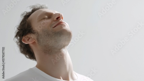 A man feeling relief, exhaling deeply, eyes closed, shoulders relaxed, clean white studio setup