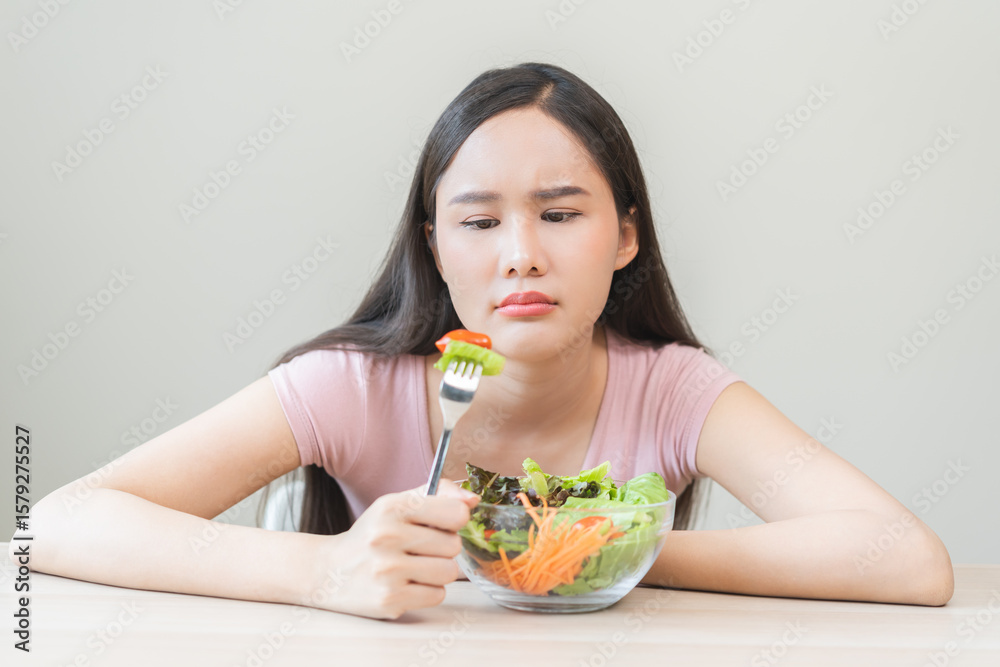 Diet in bored face, unhappy beautiful asian young woman, girl on dieting, holding fork at tomato on salad plate, dislike or tired with eat fresh vegetables. Nutrition of clean, healthy food good taste Diet in bored face, unhappy beautiful asian young woman, girl on dieting, holding fork at tomato on salad plate, dislike or tired with eat fresh vegetables. Nutrition of clean, healthy food good taste