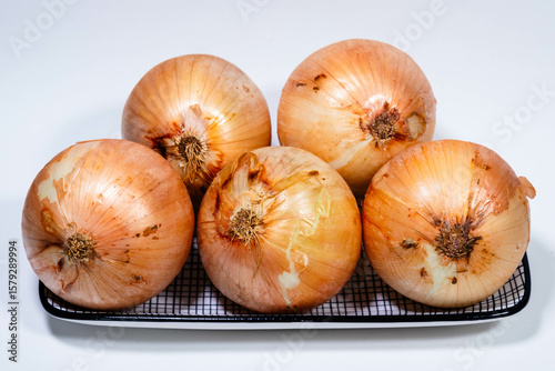 Bandeja com cebolas frescas, prontas para uso na cozinha do dia a dia.
