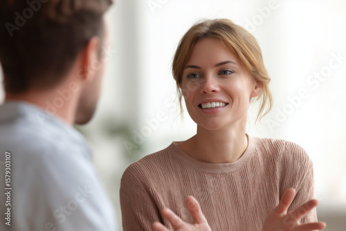 casual conversation, a person describing something with hand gestures, the other person listening attentively with slight smile