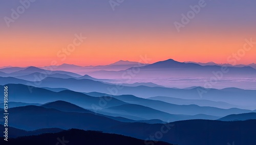 Serene sunrise over layered, hazy mountain ranges, exhibiting a gradient of blue and purple hues in the sky and deepening blues in the distant mountains