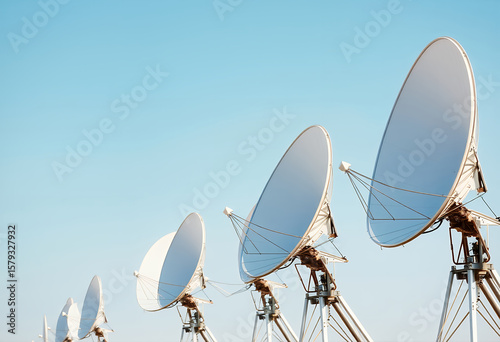 Array of Satellite Dishes Reaching for the Sky: A line of satellite dishes is angled toward the bright blue sky, representing communication.
