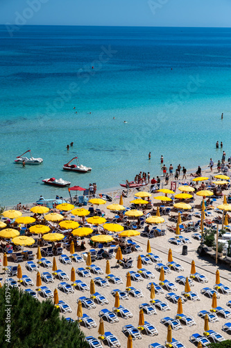 Fototapeta Naklejka Na Ścianę i Meble -  Sunny day, view on sunbeds and umbrellas on Mondello Beach, near Palermo in Sicily, popular seaside destination with fine, golden sand, turquoise waters and charming villas