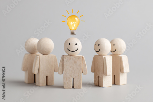 A team of wooden figures stands together, one with a bright lightbulb above, symbolizing a great idea