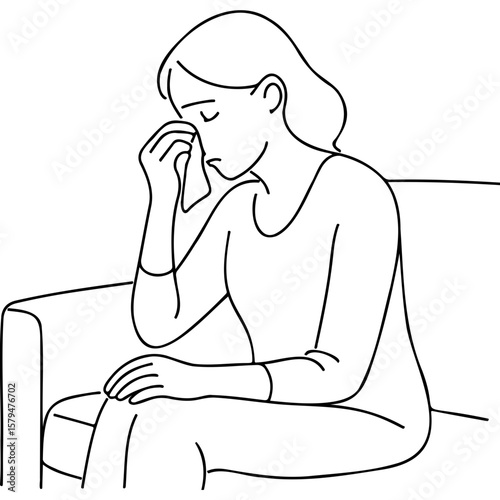 Woman sitting on couch wiping tears with cloth in emotional state  
