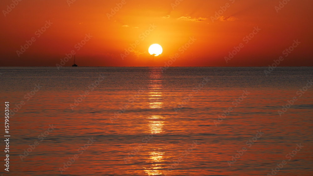Vivid sunset over the sea with a glowing sun and golden reflection on the calm water. Peaceful and captivating atmosphere. Nature background, relaxation concept, travel theme and inspirational visual Vivid sunset over the sea with a glowing sun and golden reflection on the calm water. Peaceful and captivating atmosphere. Nature background, relaxation concept, travel theme and inspirational visual