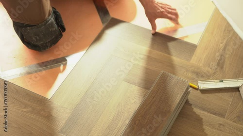 Laying of quartz vinyl flooring during renovation in an apartment or house, in the form of a Christmas tree. Laminate or quartz vinyl coating in dark color with a wood pattern. High quality 4k footage