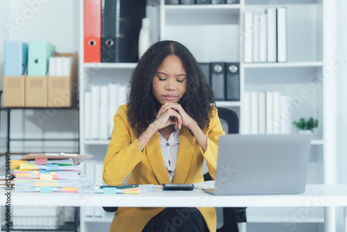Fototapete Task of Deep Reflection: A woman with a serious and concentrated expression, absorbed in thought at her desk