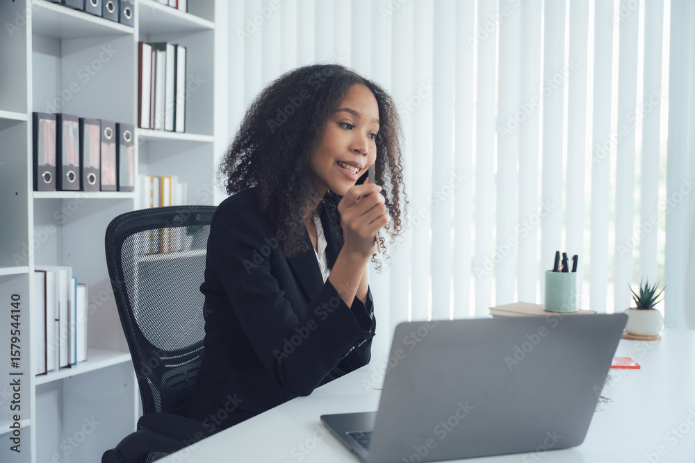 Focused Businesswoman in Conversation: A professional woman, absorbed in a business discussion via a laptop, exudes confidence and focus in a modern office setting. Focused Businesswoman in Conversation: A professional woman, absorbed in a business discussion via a laptop, exudes confidence and focus in a modern office setting.