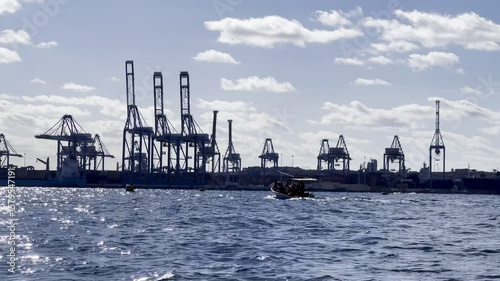 Malta freeport container terminal, birżebbuġa, malta, with moving tourist boat