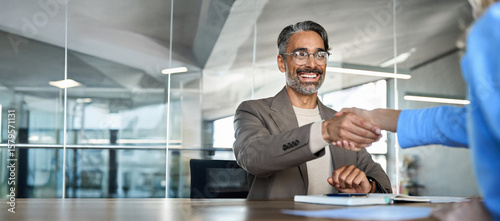 Photos Mature smiling happy professional business man executive, male hr recruiter or bank manager hiring recruit at job interview onboarding corporate office meeting