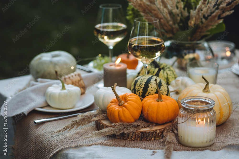 Fototapeta premium Fall table decoration with pumpkins, wine. Family thanksgiving dinner arrangement outdoors in the garden. Countryside style, simple handmade setting, autumn mood, inspiration