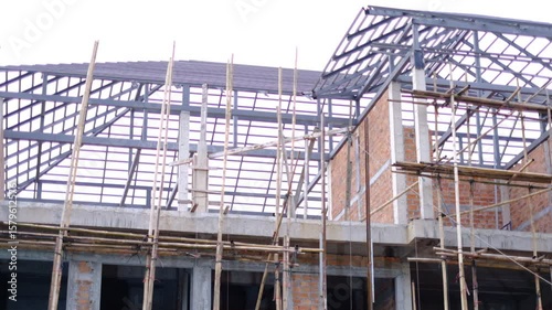 Wallpaper Mural A building under construction with scaffolding and bamboo poles. The building is made of bricks and has a slanted roof Torontodigital.ca