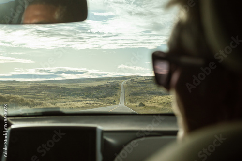silhouette of a woman in a car on a hilly road at sunset