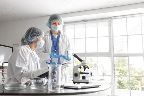 Female scientists working with Petri dish at table in laboratory
