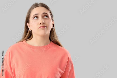 Thoughtful woman on grey ba...