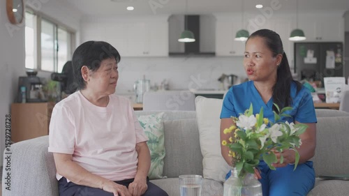 Asian health care worker giving elderly woman physiotherapy at home, home nurse, home care service concept
