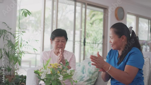 Asian health care worker giving elderly woman physiotherapy at home, home nurse, home care service concept
