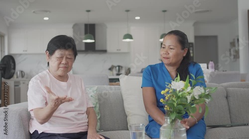 Asian health care worker giving elderly woman physiotherapy at home, home nurse, home care service concept
