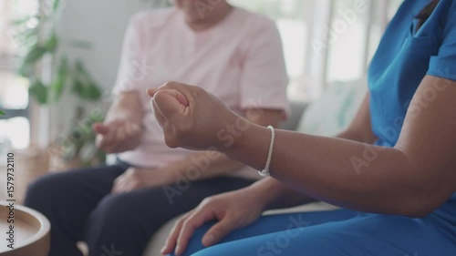 Asian health care worker giving elderly woman physiotherapy at home, home nurse, home care service concept
