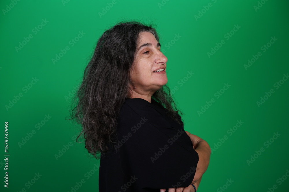 Fototapeta premium Woman with a variety of emotions, wearing a black t-shirt ,standing against a green background. Studio shot with copy space. Not edited image