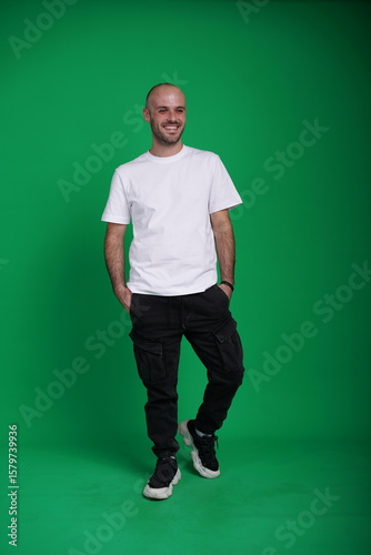 Young man with a variety of emotions, wearing a white t-shirt standing against a green background. Studio shot with copy space.