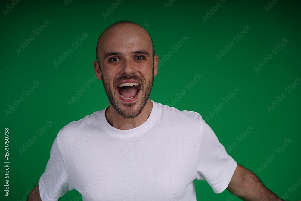 Fototapeta premium young man wearing a white t-shirt standing against a green background. Studio shot with copy space.