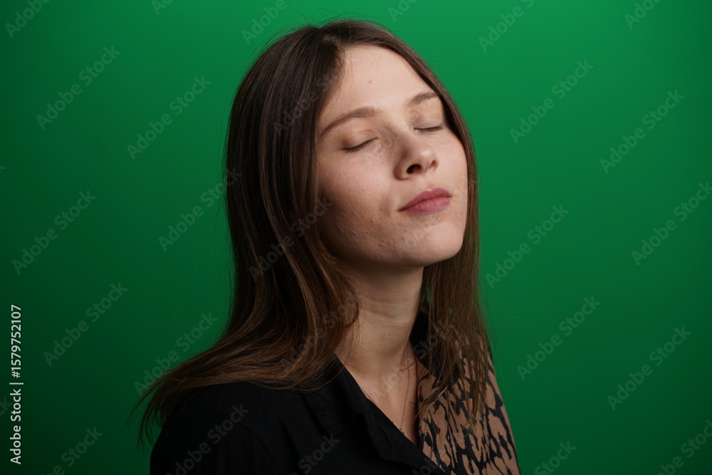 A young woman poses in a studio with a green background, showing natural emotions, full of expressions and dynamic movements. Unedited image A young woman poses in a studio with a green background, showing natural emotions, full of expressions and dynamic movements. Unedited image
