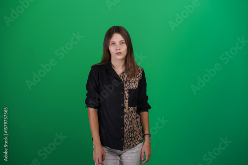 A young woman poses in a studio with a green background, showing natural emotions, full of expressions and dynamic movements. Unedited image