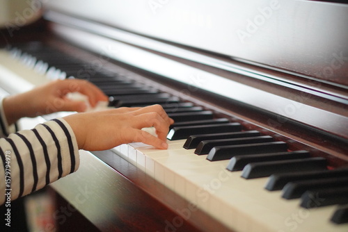 ピアノの鍵盤に触れる子どもの手が奏でる音楽への第一歩、楽器演奏を通じて感性と創造性を育む音楽教育の美しい瞬間、白と黒の鍵盤が生み出す無限の可能性への扉を開く貴重な体験。7歳小学2年生。