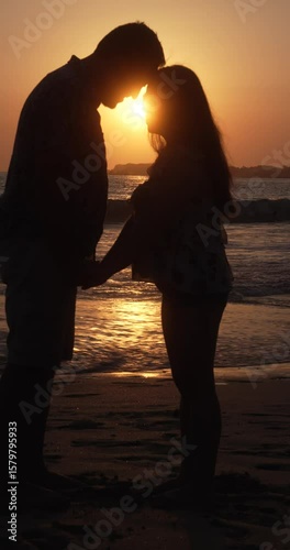 Couple's sihouete kiss by the beach at the sunset