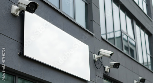 Surveillance Cameras Installed on Modern Building with Empty Advertising Board Space in Urban Environment