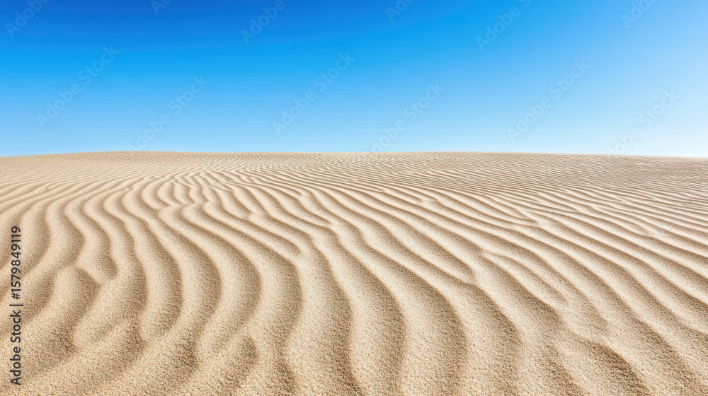 Naklejka premium Smooth sand dunes create serene landscape under clear blue sky, evoking tranquility and beauty