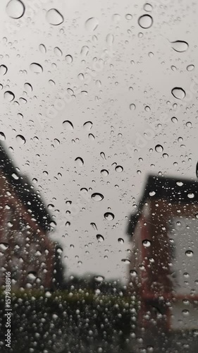 A macro capture of wet blue raindrops on a transparent glass window surface creates an abstract liquid texture