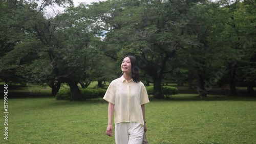 公園を散歩しながら森林浴をする笑顔の女性のフォローショット
