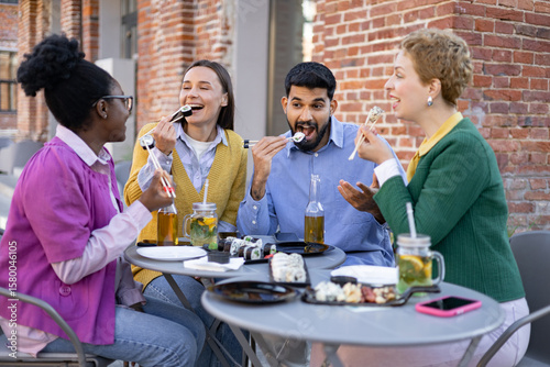 Friends enjoy sushi and drinks together at an outdoor restaurant.