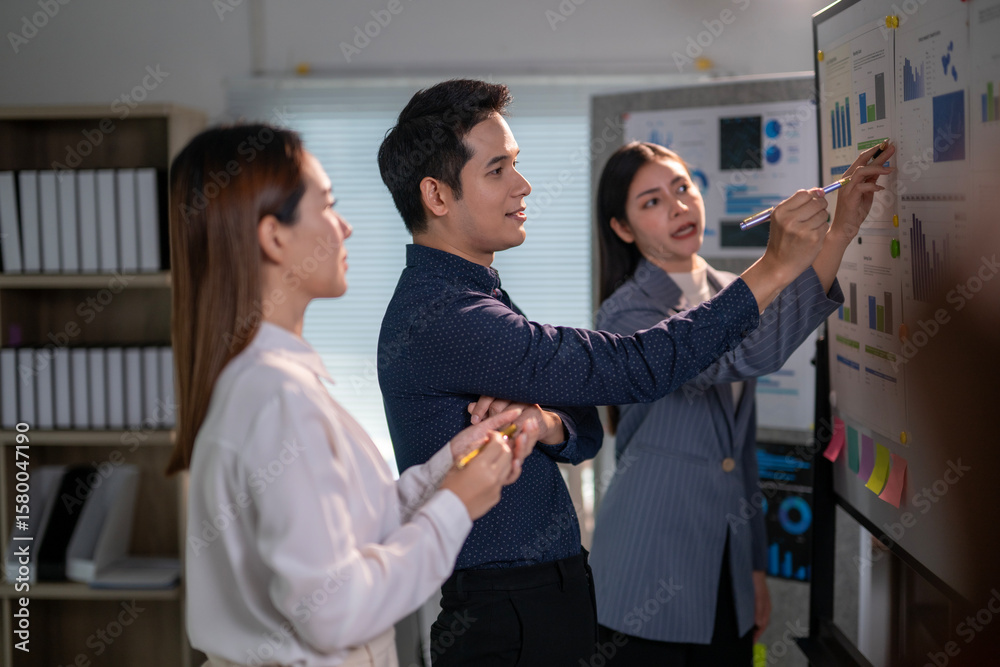 Fototapeta premium Three people are standing in front of a whiteboard with graphs and writing on it