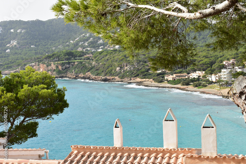 Fototapeta Naklejka Na Ścianę i Meble -  Türkises Wasser in der Bucht von Canyamel auf Mallorca mit den Dächern von Ferienhäusern im Vordergrund