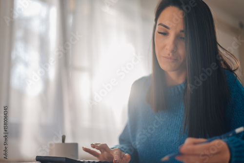 Focused accountant managing finances with calculator and pen in home office Free Download Focused accountant managing finances with calculator and pen in home office - GFXLoad